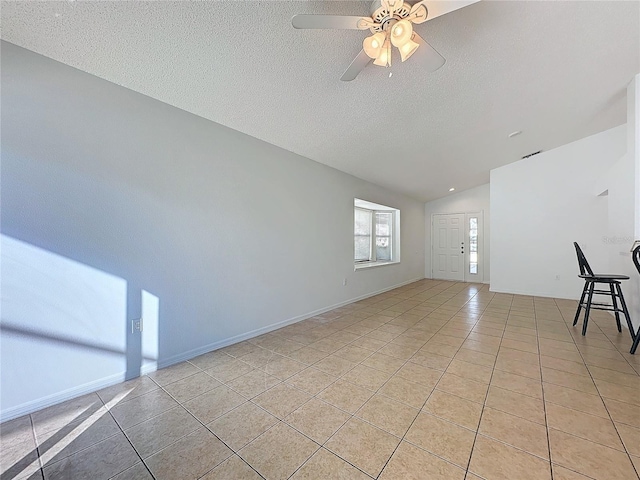 interior space with light tile patterned floors, a textured ceiling, and vaulted ceiling