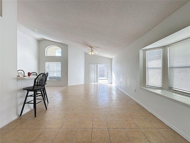 tiled empty room featuring a textured ceiling, ceiling fan, and vaulted ceiling