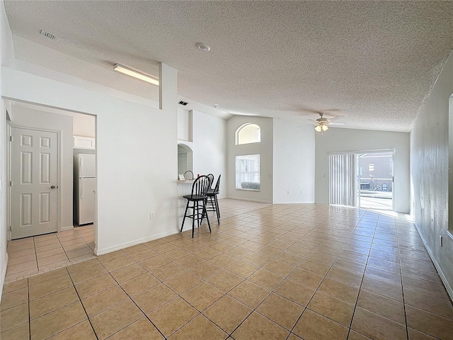 spare room with plenty of natural light, ceiling fan, light tile patterned floors, and a textured ceiling