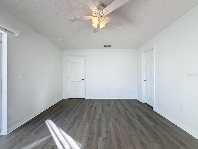 empty room featuring dark hardwood / wood-style floors, ceiling fan, and a textured ceiling