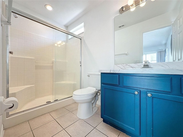 bathroom featuring tile patterned floors, vanity, toilet, and a shower with door