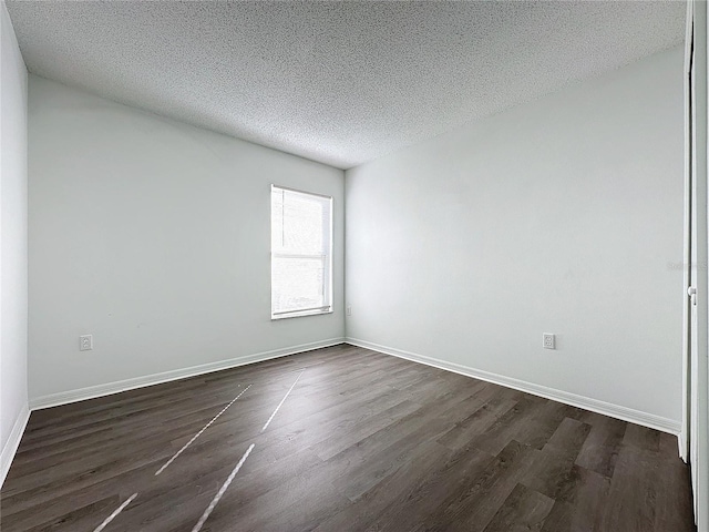 spare room with dark hardwood / wood-style floors and a textured ceiling