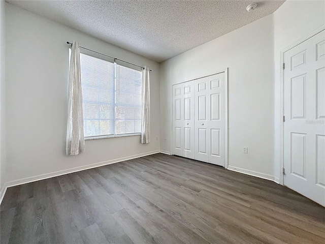 unfurnished bedroom featuring hardwood / wood-style floors, a textured ceiling, and a closet