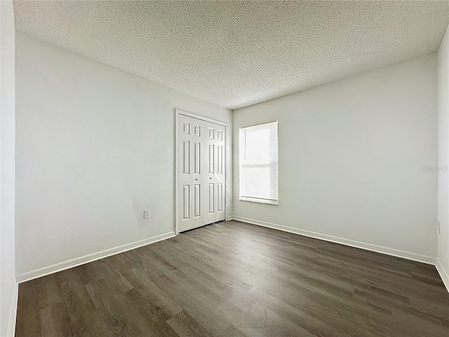 unfurnished bedroom featuring a textured ceiling and dark hardwood / wood-style floors