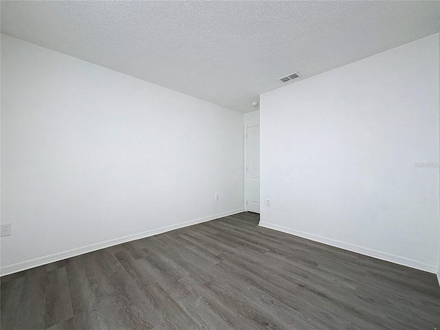 empty room featuring a textured ceiling and dark hardwood / wood-style floors