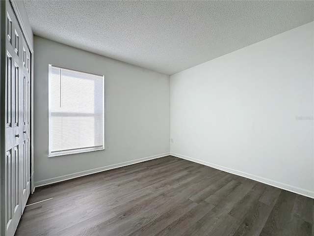 spare room featuring dark hardwood / wood-style flooring and a textured ceiling