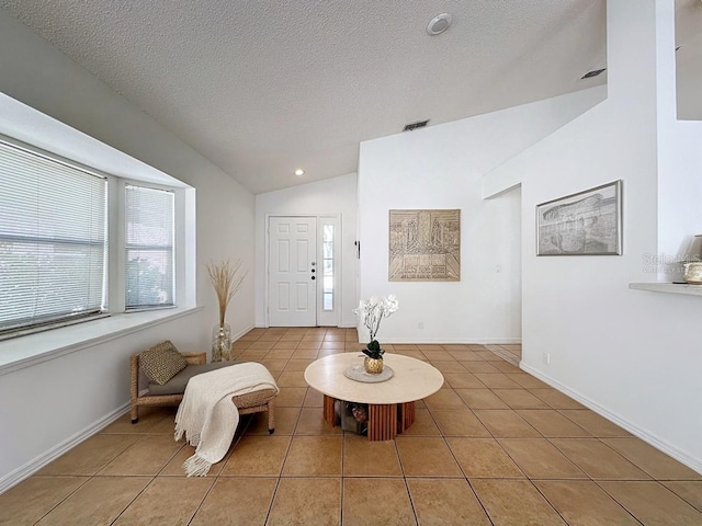 living area with a textured ceiling, vaulted ceiling, and light tile patterned flooring