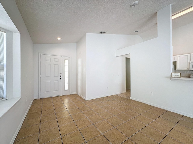 tiled foyer with a textured ceiling and lofted ceiling