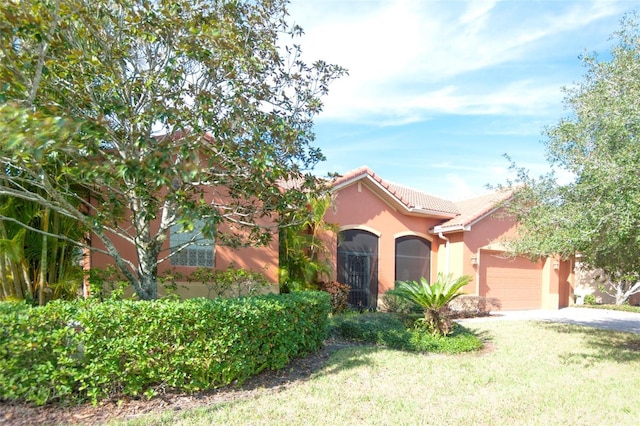 mediterranean / spanish-style house with a tile roof, stucco siding, concrete driveway, an attached garage, and a front yard