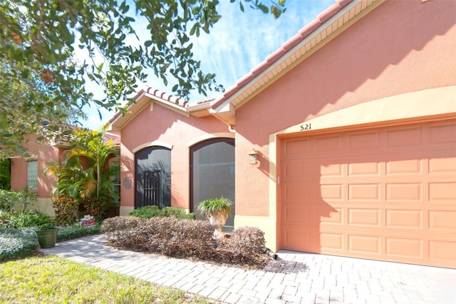 exterior space featuring a garage, a tiled roof, and stucco siding