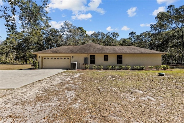 ranch-style home featuring a garage and cooling unit