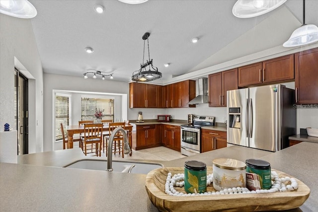 kitchen with wall chimney exhaust hood, stainless steel appliances, sink, decorative light fixtures, and lofted ceiling