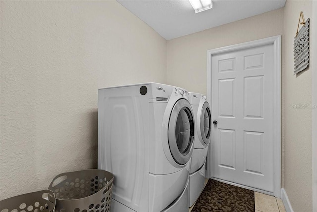 clothes washing area featuring washer and clothes dryer and light tile patterned floors