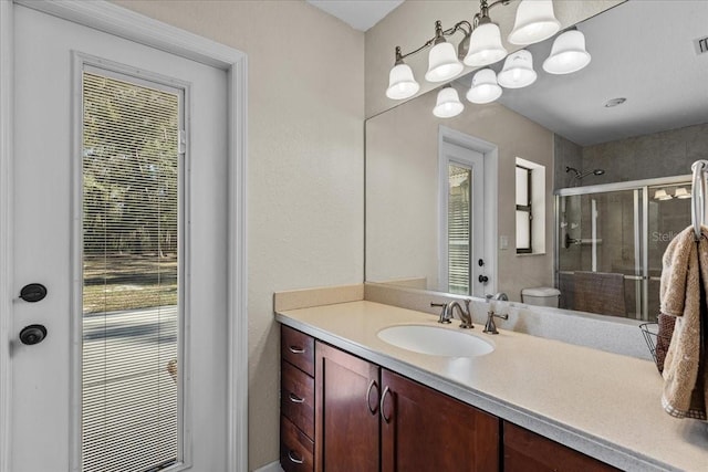 bathroom with a chandelier, vanity, toilet, and walk in shower