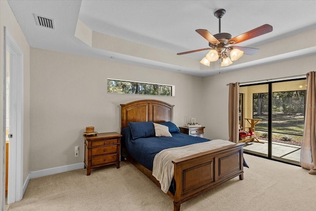 bedroom featuring multiple windows, access to outside, a tray ceiling, and ceiling fan