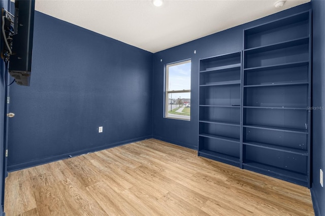 unfurnished room featuring built in features and light wood-type flooring