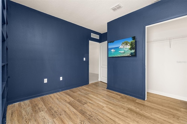 unfurnished bedroom with a textured ceiling, hardwood / wood-style flooring, and a closet