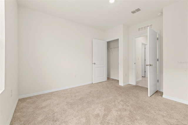 unfurnished bedroom with light carpet and a closet