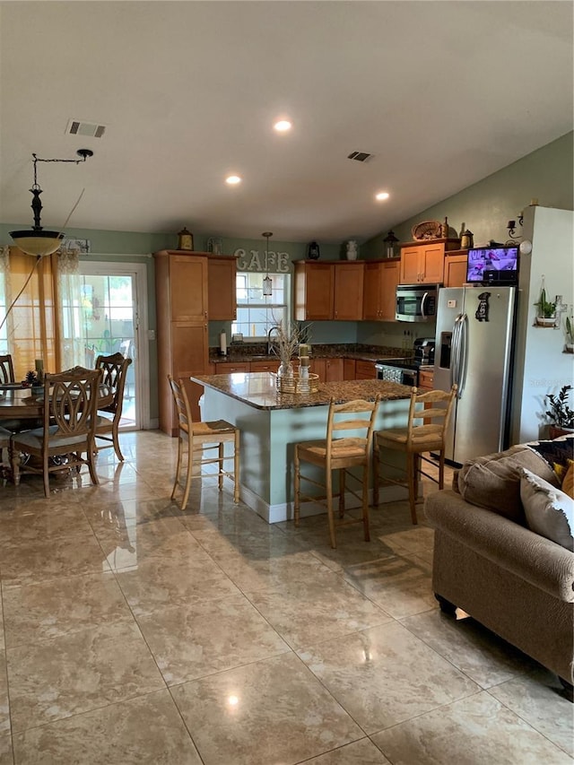 kitchen featuring lofted ceiling, a kitchen breakfast bar, hanging light fixtures, a kitchen island, and stainless steel appliances