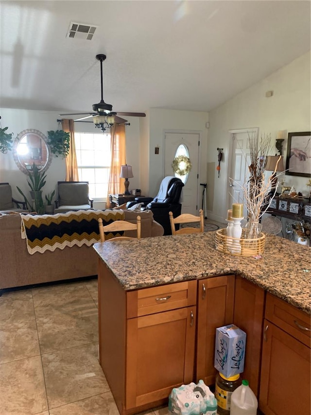 kitchen featuring light tile patterned floors, light stone counters, ceiling fan, and lofted ceiling