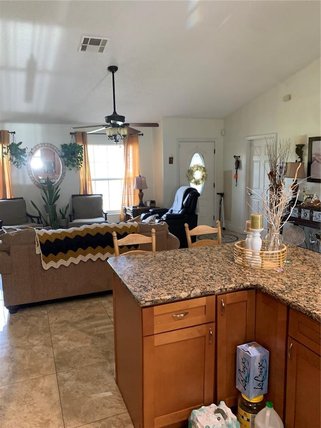 kitchen featuring lofted ceiling, stone counters, ceiling fan, and light tile patterned floors