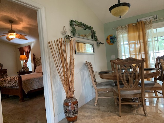 tiled dining space with ceiling fan and lofted ceiling