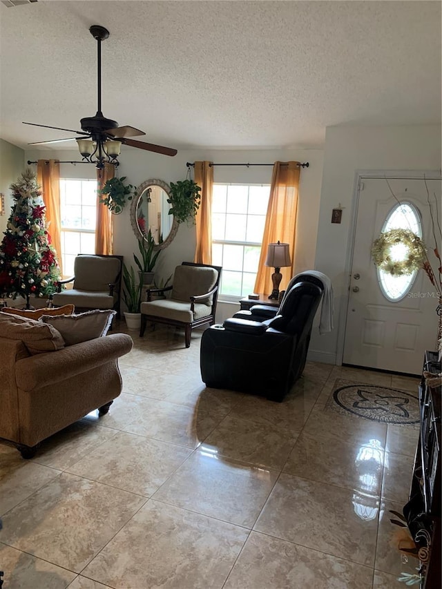 tiled living room featuring ceiling fan, a healthy amount of sunlight, and a textured ceiling