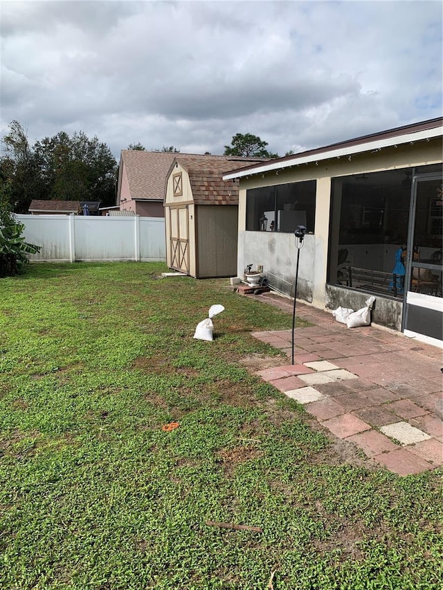 view of yard featuring a shed, a patio area, and a sunroom