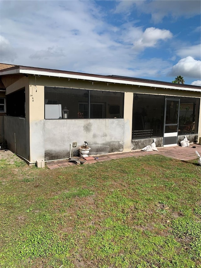 rear view of house featuring a lawn and a sunroom