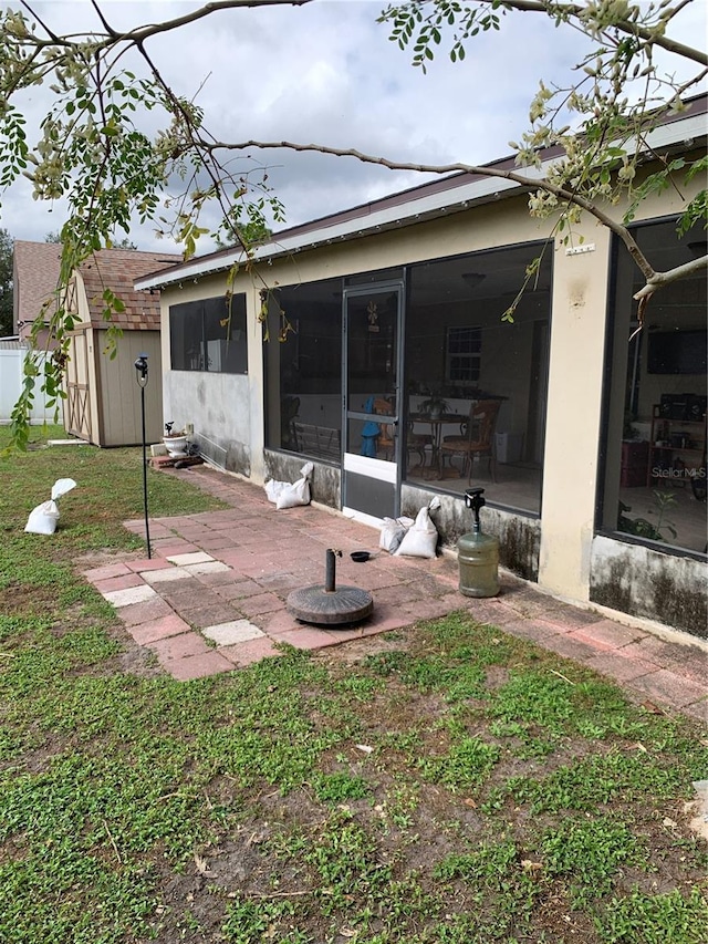 back of property featuring a patio, a lawn, and a sunroom