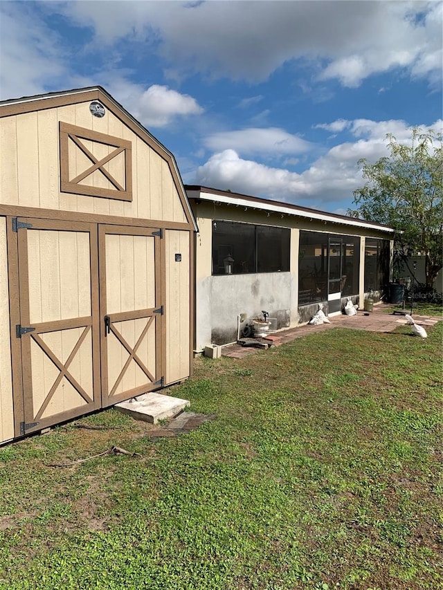 view of outbuilding featuring a yard and a sunroom