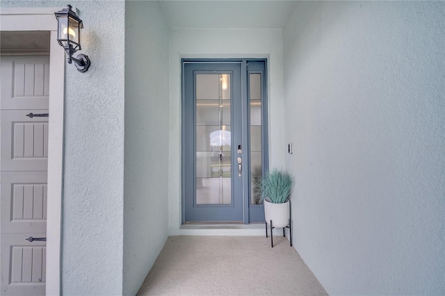 doorway to property with a garage and stucco siding