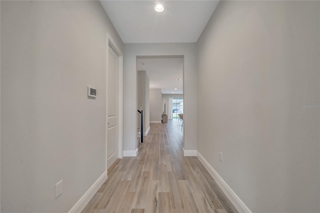 corridor with light wood-style floors and baseboards