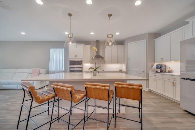 kitchen featuring light countertops, wall chimney range hood, and white cabinets