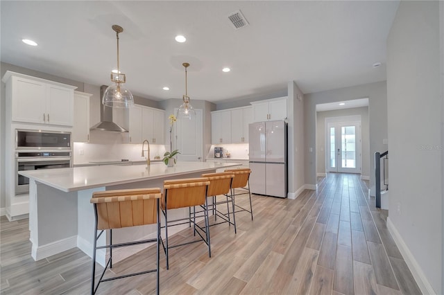 kitchen featuring freestanding refrigerator, white cabinets, visible vents, and built in microwave