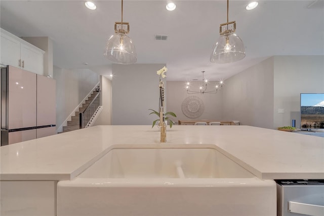 kitchen featuring light countertops, visible vents, a sink, and hanging light fixtures