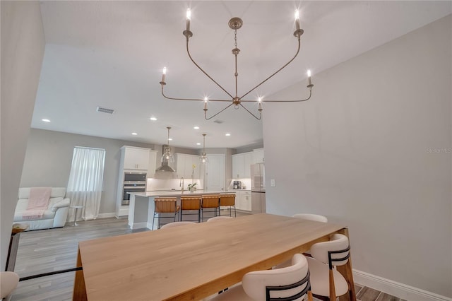 dining area with light wood-style floors, baseboards, and visible vents