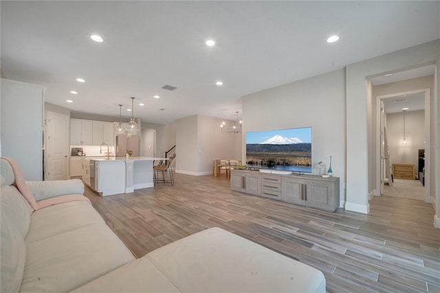 living room with light wood finished floors, baseboards, visible vents, a notable chandelier, and recessed lighting