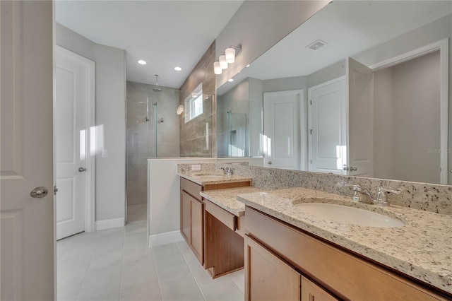 bathroom with visible vents, vanity, tiled shower, baseboards, and tile patterned floors