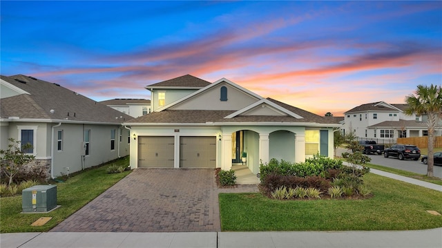 view of front of house with decorative driveway, covered porch, a yard, and stucco siding