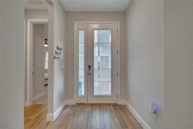 entryway with baseboards, visible vents, and light wood finished floors