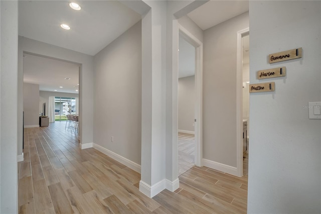 hallway featuring light wood-type flooring, baseboards, and recessed lighting