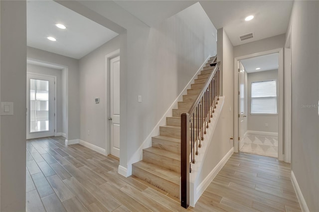 stairway with baseboards, visible vents, wood finished floors, and recessed lighting