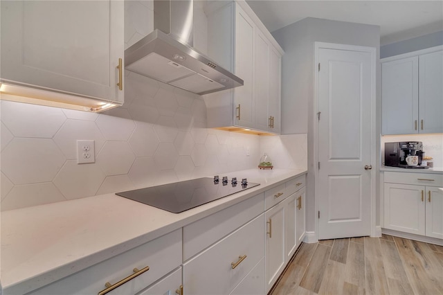 kitchen featuring light countertops, white cabinetry, wall chimney exhaust hood, and black electric cooktop