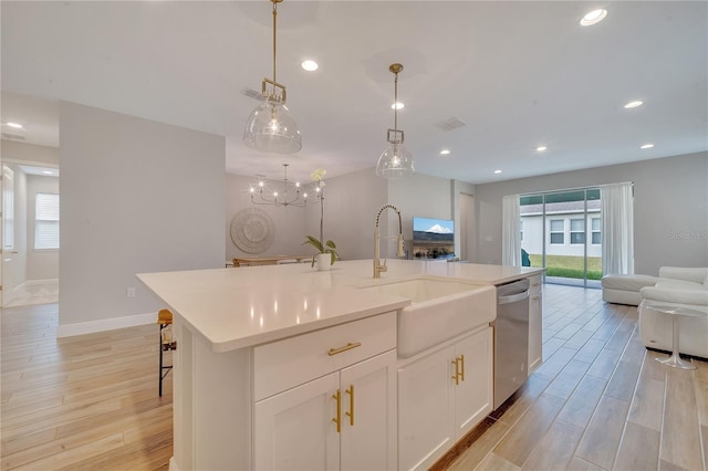 kitchen with dishwasher, light wood finished floors, open floor plan, and a sink