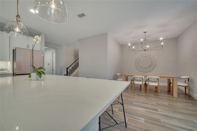 dining space with visible vents, stairway, a chandelier, light wood-type flooring, and baseboards