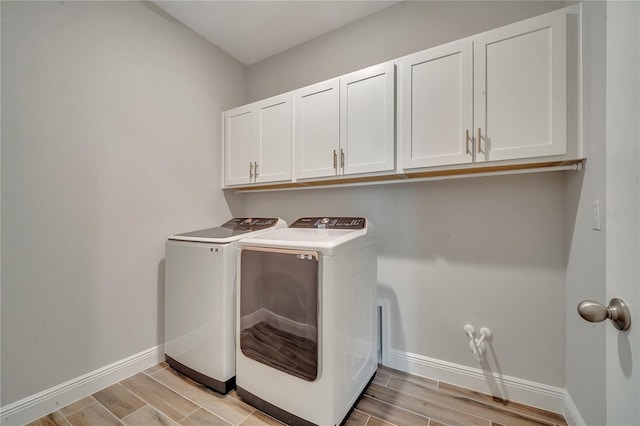 laundry room with baseboards, washing machine and clothes dryer, cabinet space, and wood tiled floor