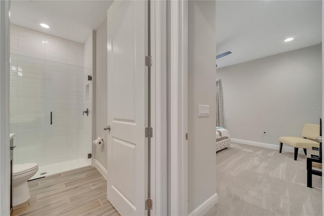 bathroom featuring baseboards, connected bathroom, toilet, a shower stall, and recessed lighting