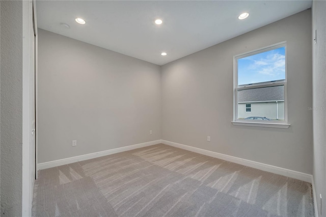 empty room featuring recessed lighting, light carpet, and baseboards