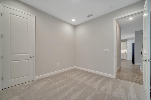 spare room with baseboards, recessed lighting, visible vents, and light colored carpet